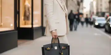 Elegant woman with a black Hermes Birkin bag, showcasing luxury fashion investment.